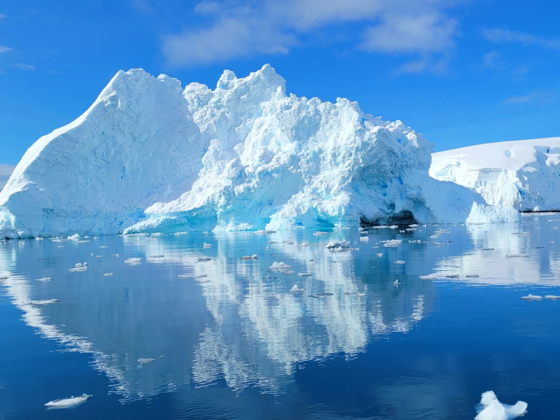 Large iceberg reflecting in calm blue water