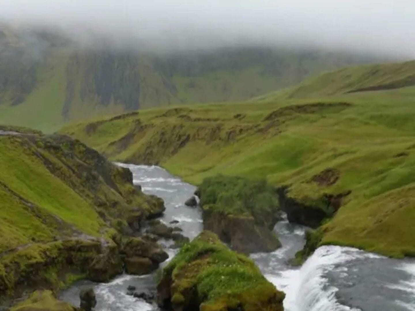 Misty green hills with river and waterfall